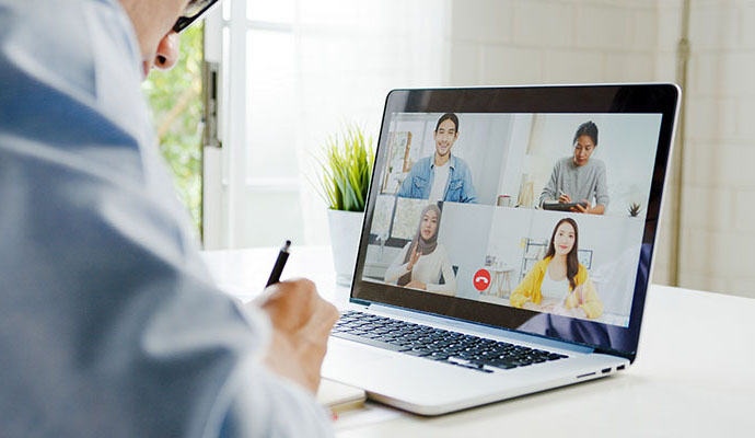 Young Asia businessman using laptop talk to colleagues about plan in video call meeting while work from home at living room. Self-isolation, social distancing, quarantine for corona virus prevention.